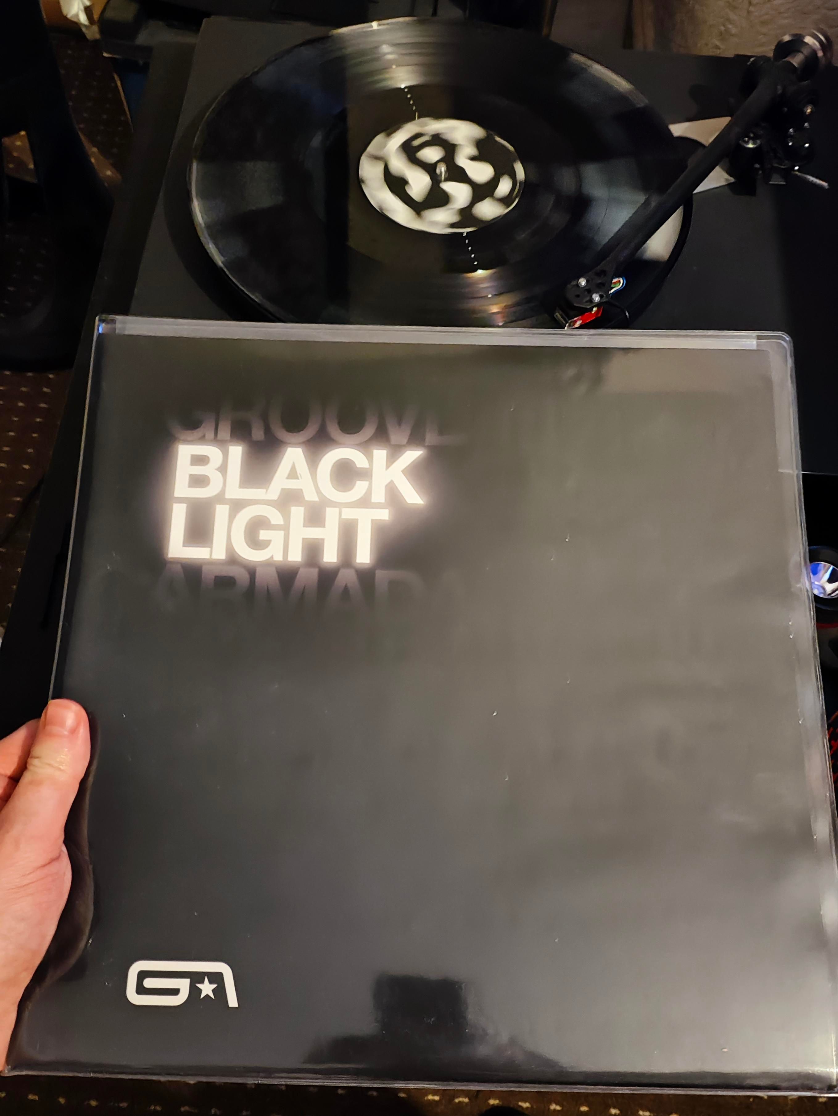 Plain black cover with title shown in theme with black light effect and white Splatter on black record playing 