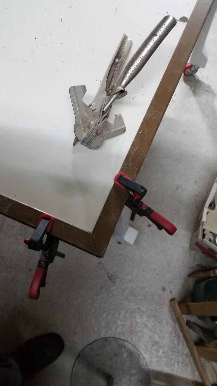 Piano del tavolo semovente con paraspigoli in PVC color noce (dice d'etichetta).
A fianco le cesoie per fare i tagli a 45°.