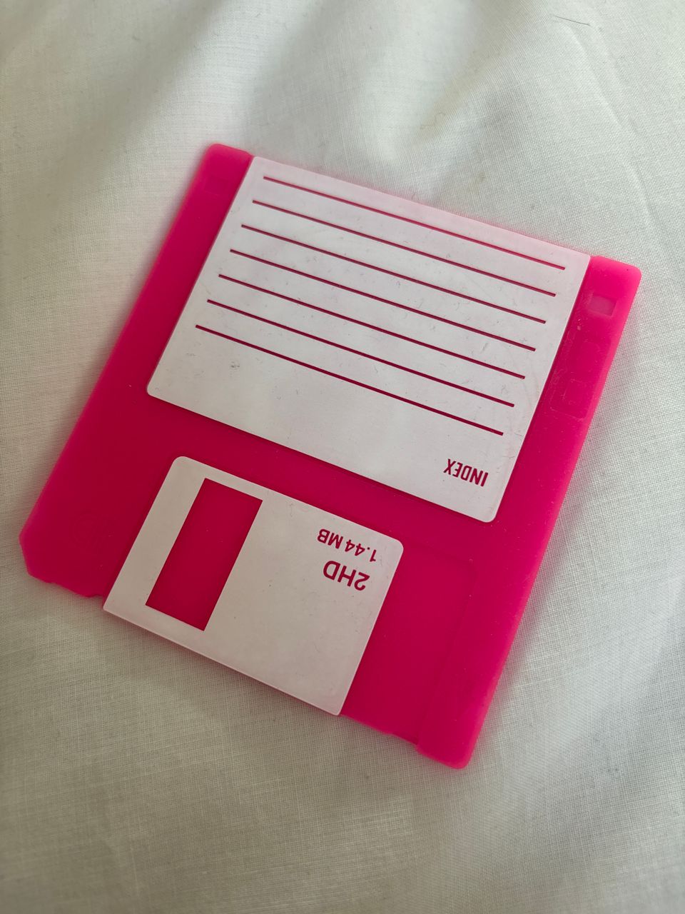 A silicone coaster realistically shaped and decorated like a 3.5” floppy disk.