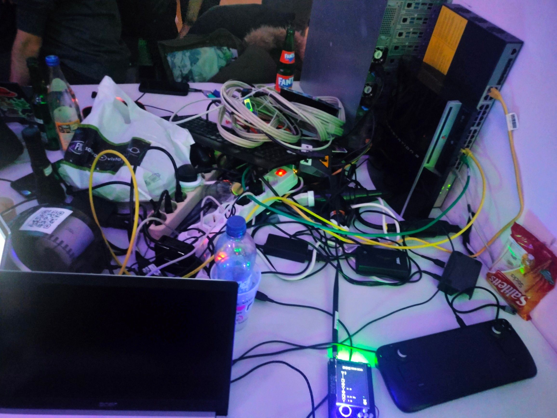 a small table completely overflowing with cables and random pcs and electronic things