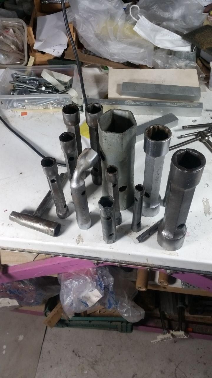 Numerose chiavi a tubo appoggiate in verticale sul tavolo da lavoro.