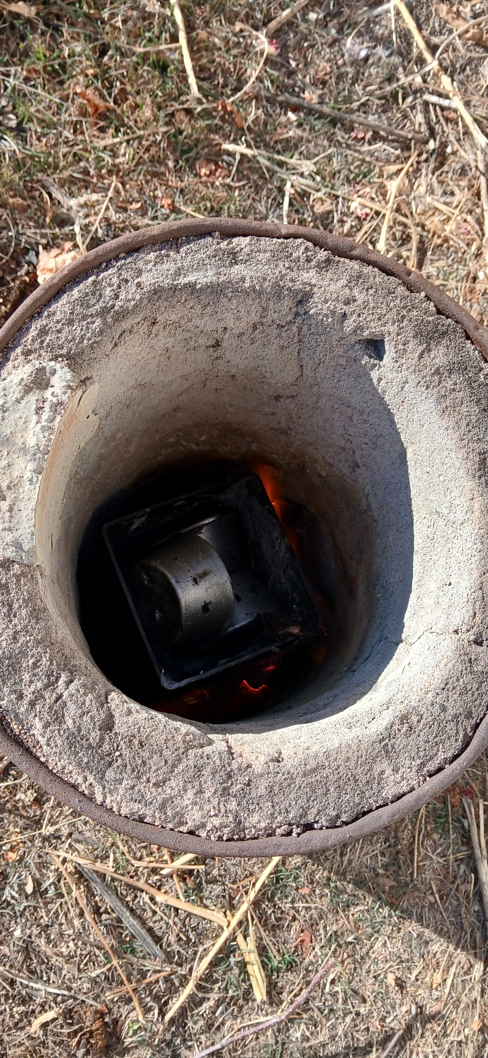 The depths of the furnace with a flame visible and some shiny aluminum in the crucible 