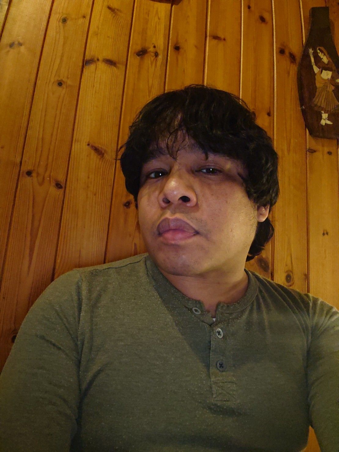 Asian lad in "late youth" (lol) perched on a staircase looking at the camera with a 1970s wooden panel wall in background