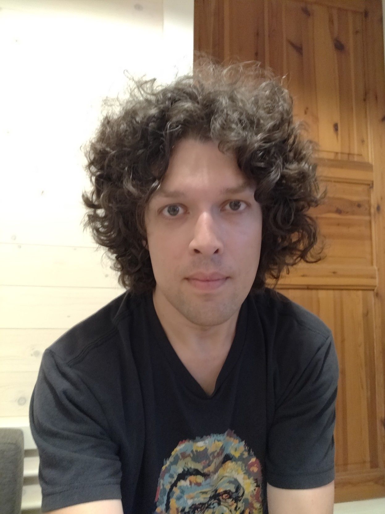 me sitting, looking at the camera, in a black t-shirt with a multicoloured gorilla head on it.