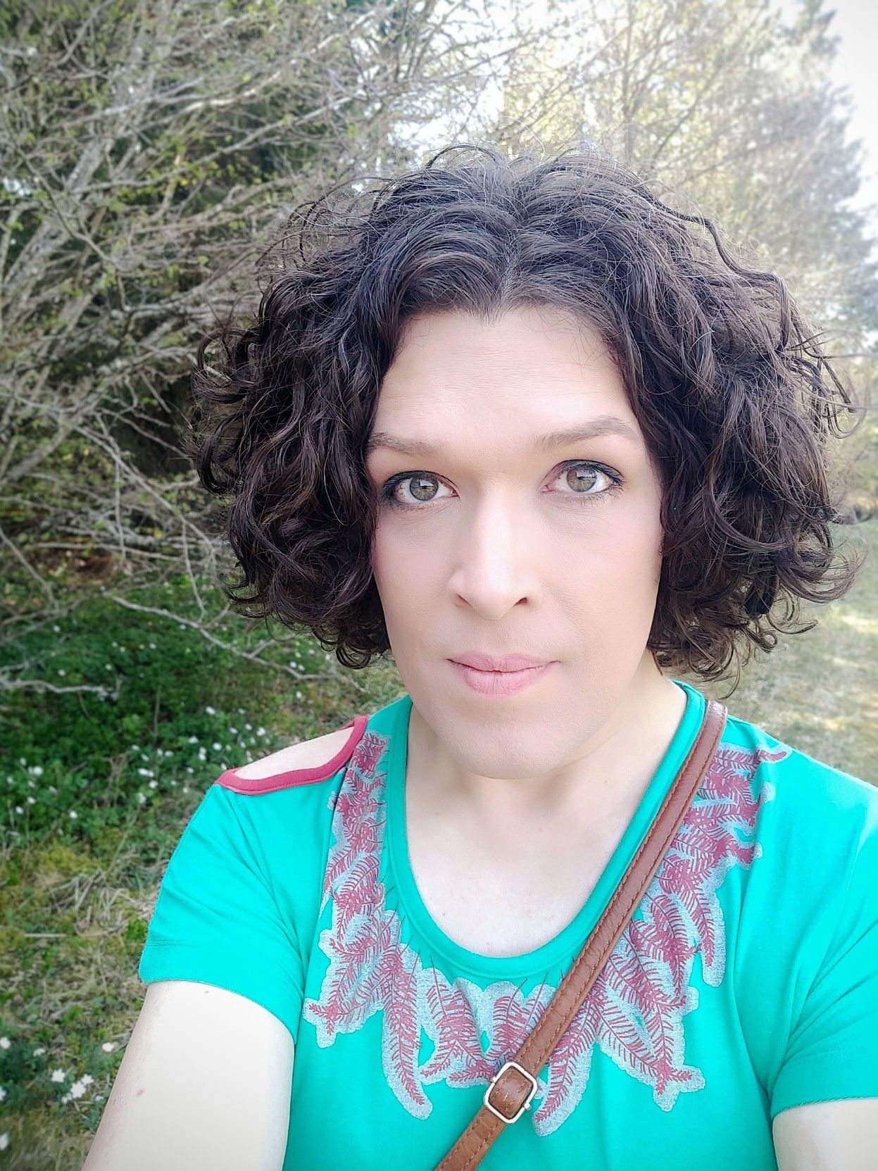 me outside in the summer, in a green dress with a red feather pattern around the neckline