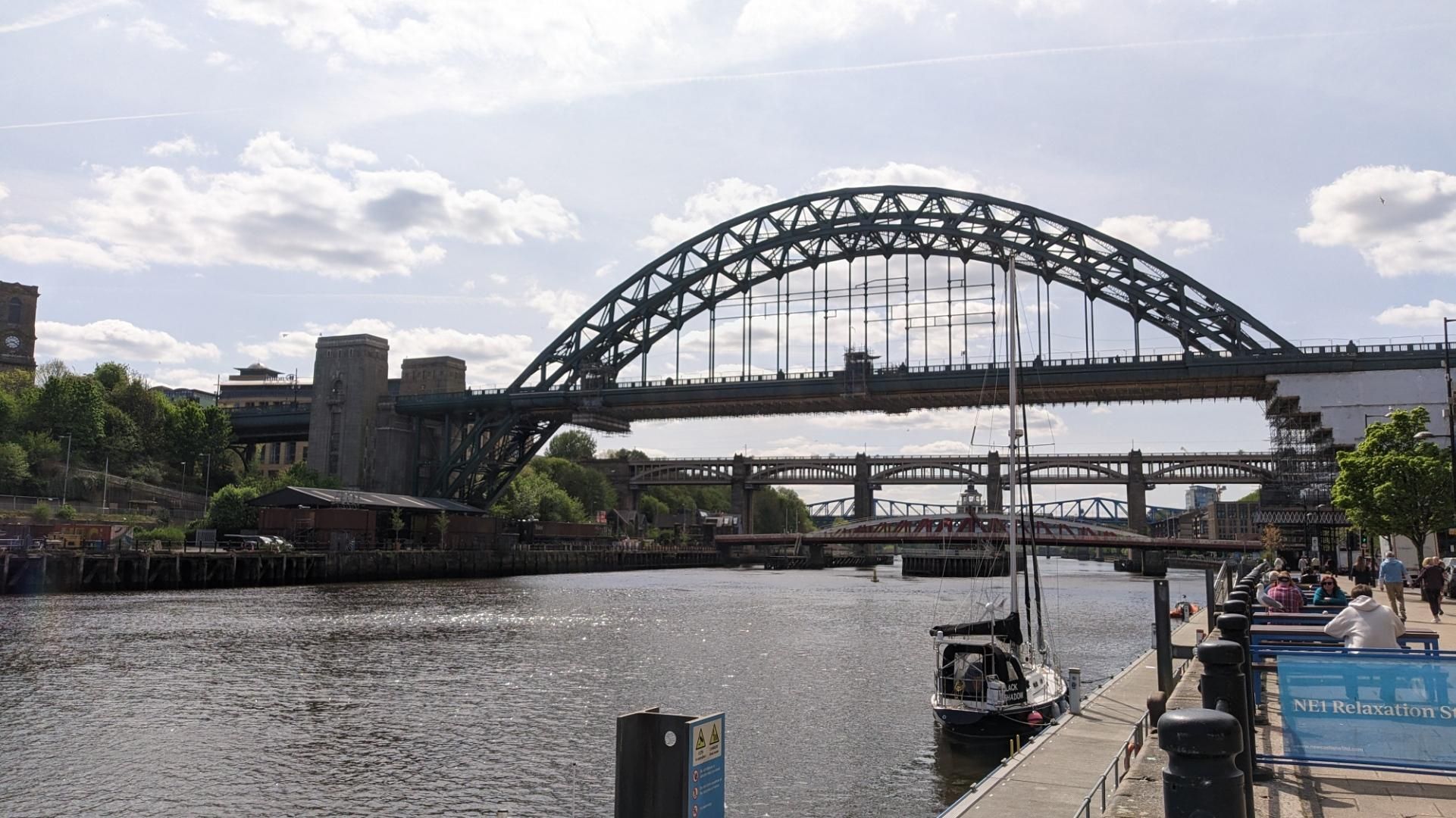 Four bridges over the river. In the distance a blue steel bridge, then a high double Land steel bridge, a swing bridge on the lower level and another steel bridge