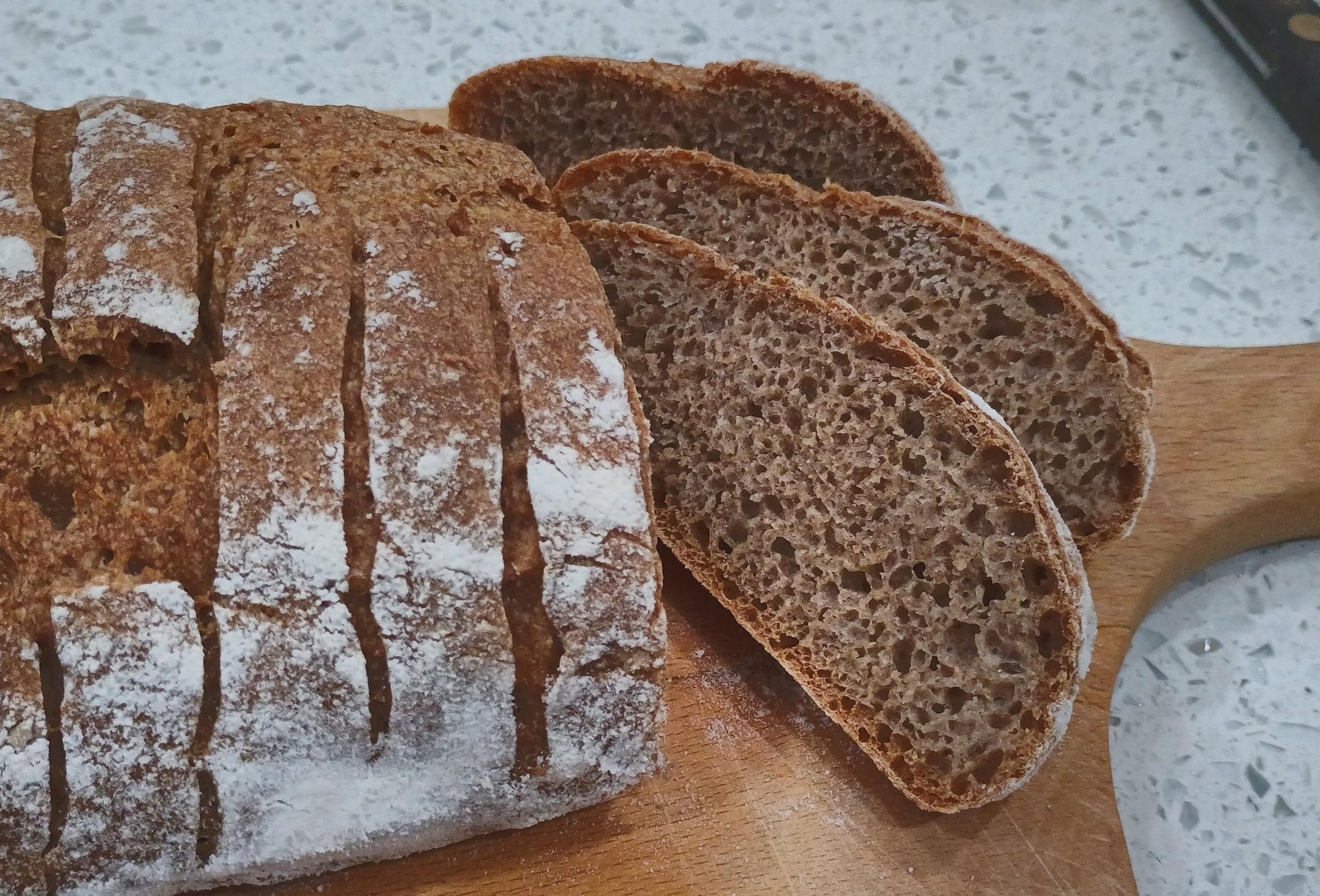 The end of a loaf is sliced and the inside bread crumb is bubbly and rich looking