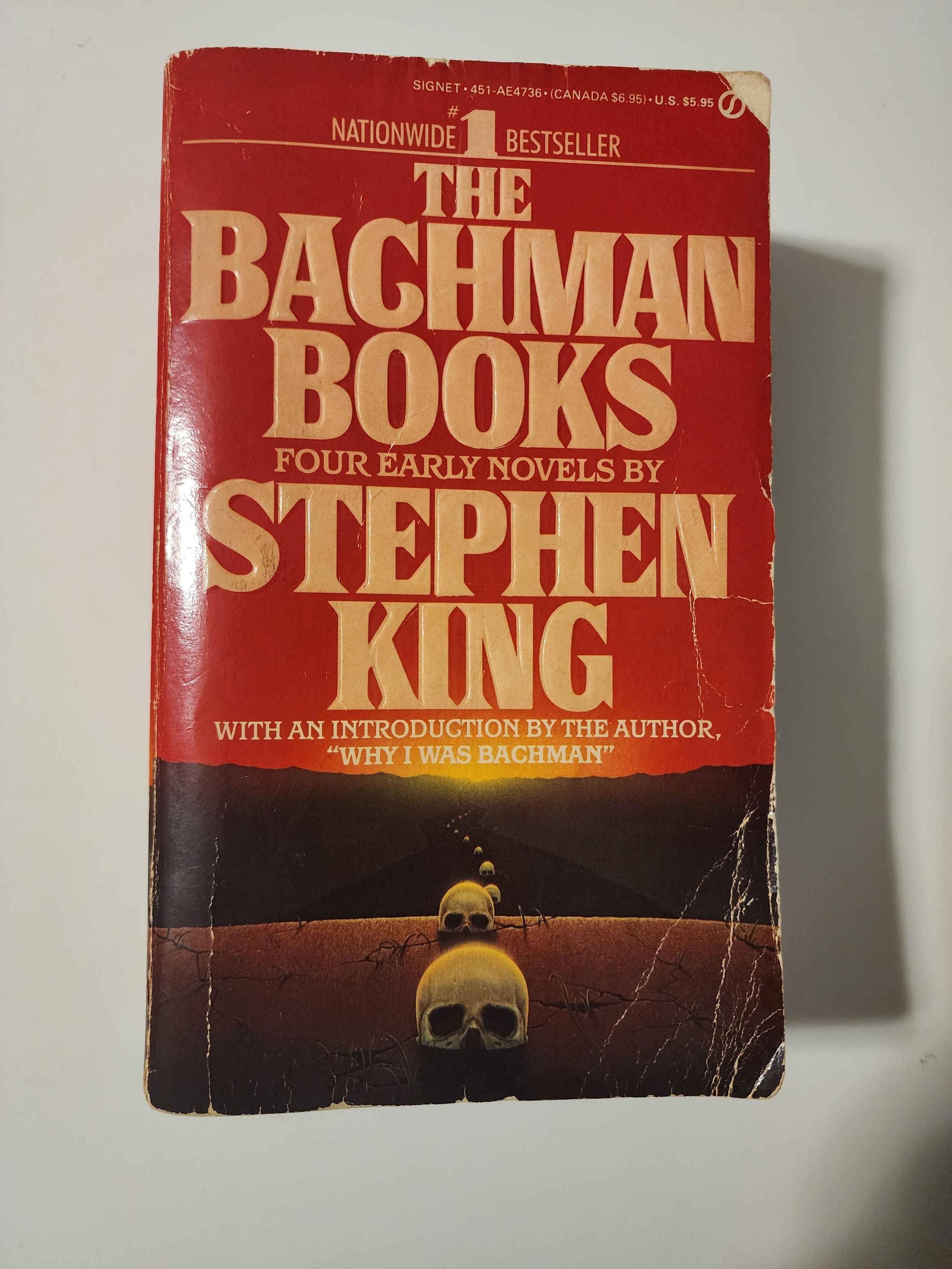 The Bachman Books by Stephen King. Paperback. An orange cover with skulls on a road. A sunset in the distance.